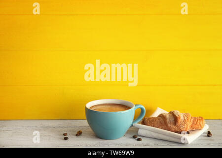 Caffè e cornetto con sparsi i chicchi di caffè su sfondo di legno Foto stock  - Alamy