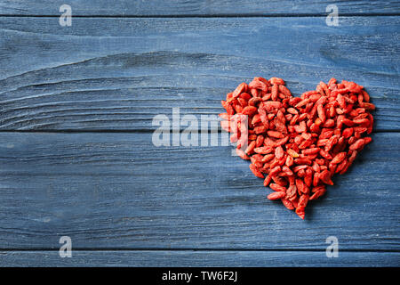 Cuore di goji bacche su sfondo di legno Foto Stock