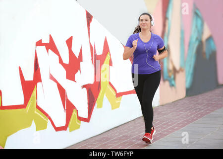 Il sovrappeso giovane donna fare jogging in strada. La perdita di peso concept Foto Stock