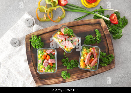 Insalata di verdure con salsiccia in ciotole in vetro sulla tavola di legno Foto Stock