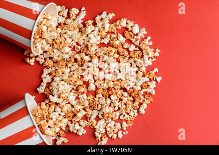 Bicchieri rovesciati con gustosi caramello popcorn sul colore di sfondo Foto Stock