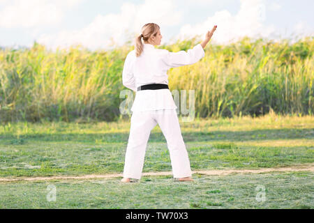 Giovane donna a praticare il karate all'aperto Foto Stock