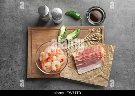 Composizione con materie di gamberetti e pancetta sul tavolo Foto Stock