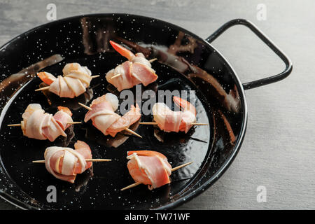 Padella con pancetta di gamberi avvolti sul tavolo Foto Stock