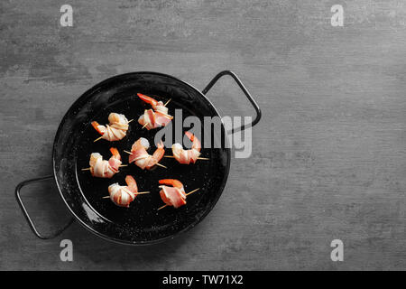 Padella con pancetta di gamberi avvolti sul tavolo Foto Stock