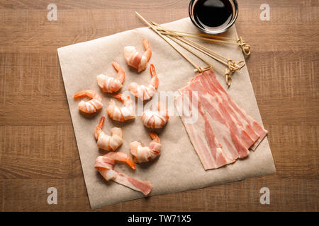 Composizione con materie di gamberetti e pancetta sul tavolo Foto Stock