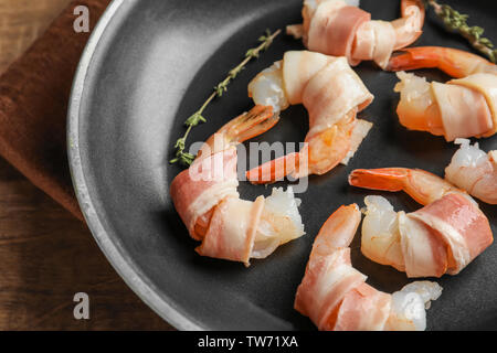 Padella con pancetta di gamberi avvolti su un tavolo di legno, primo piano Foto Stock