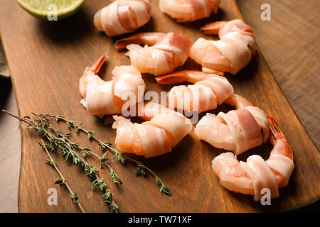 Tavola di legno con pancetta di gamberi avvolti su tavola, primo piano Foto Stock