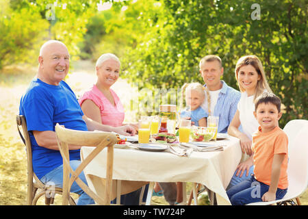 La famiglia felice avente il barbecue all'aperto Foto Stock