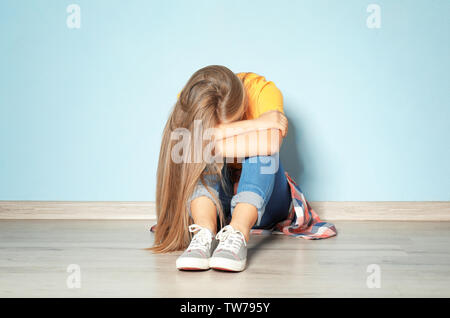 Triste adolescente ragazza seduta sul pavimento in camera vuota Foto Stock