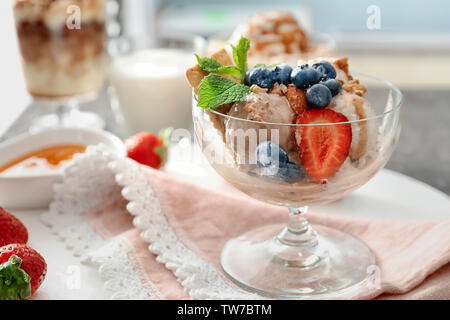 Ciotola con gelato, caramello, frutti di bosco e i dadi sul tavolo Foto Stock