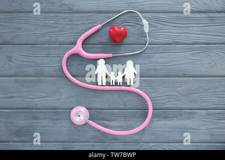 Famiglia figura, cuore rosso e uno stetoscopio su sfondo di legno Foto Stock