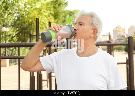 Sportivo da uomo senior bere protein shake, all'aperto Foto Stock