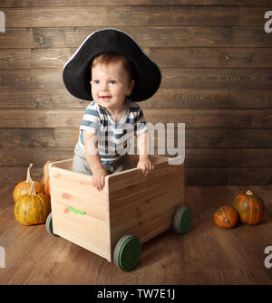 Adorable bebè in costume pirata vicino alla parete in legno. Concetto di Halloween Foto Stock