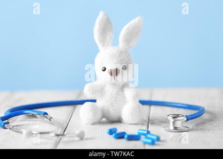 Toy bunny, pillole e uno stetoscopio sul tavolo. Concetto di pediatra Foto Stock