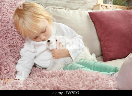 Poco carino ragazza con cucciolo in casa Foto Stock