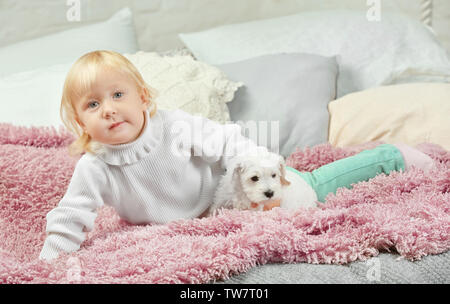 Poco carino ragazza con cucciolo in casa Foto Stock