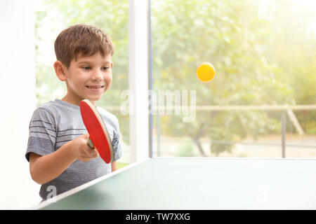 Carino piccolo ragazzo giocando a ping-pong per interni Foto Stock