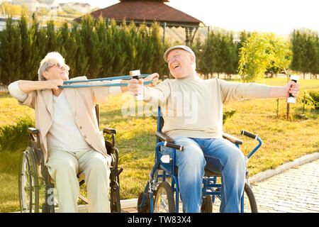 Senior l uomo e la donna dalla casa di cura facendo esercizio all'aperto Foto Stock