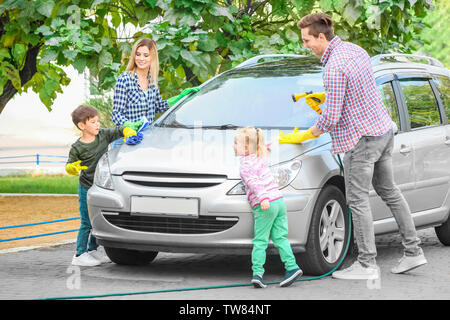 La famiglia felice il lavaggio auto all'aperto Foto Stock