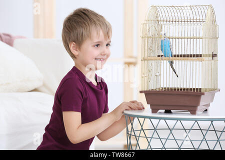 Ragazzino con pet adorabili blue parrot in gabbia in ambienti interni Foto Stock