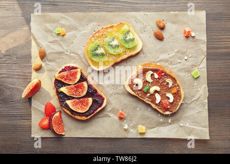 Deliziosi toast con marmellata e pasta cioccolato su pergamena Foto Stock