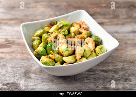 Ciotola con arrosti di carne i cavoletti di Bruxelles su sfondo di legno Foto Stock