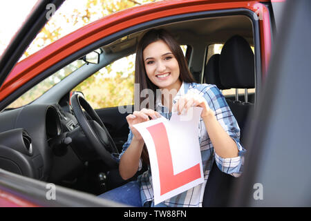 Felice giovane donna strappo allievo conducente sign in auto Foto Stock