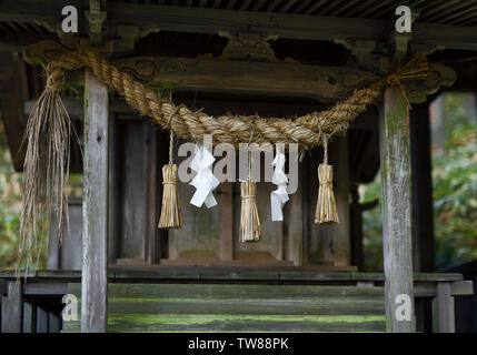 Rurale santuario scintoista di dettaglio, Shimenawa corda e carta streamers, Shide, che decorano gli oggetti. Foto Stock