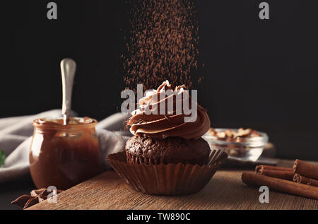 Irrorazione di gustoso cioccolato tortina sul pannello di legno Foto Stock