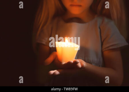 Little Girl holding candela che brucia nel buio Foto Stock