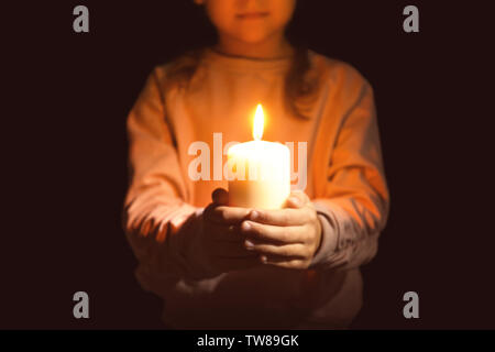 Little Girl holding candela che brucia nel buio Foto Stock