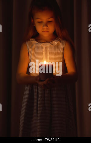 Little Girl holding candela che brucia nel buio Foto Stock