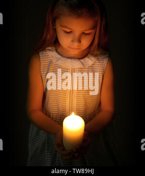 Little Girl holding candela che brucia nel buio Foto Stock