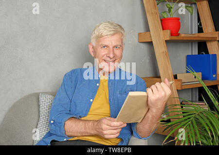 Attraente uomo maturo libro di lettura in ambienti interni Foto Stock
