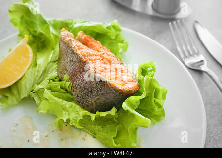 Delizioso fritto di trota arcobaleno con lattuga e salsa su piastra, primo piano Foto Stock