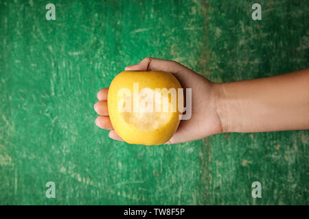 Donna che mantiene apple con marchio del morso sul verde sullo sfondo di legno Foto Stock