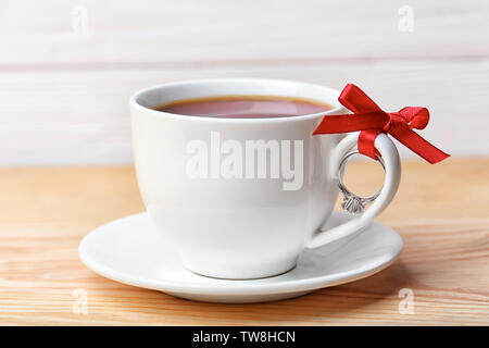 Anello di fidanzamento legata alla tazza di caffè sul tavolo, primo piano Foto Stock