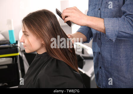 Parrucchiere maschio pettinare i capelli dei clienti in salone Foto Stock
