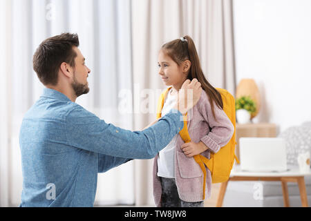 Giovane uomo aiutando la figlia ottenere pronto per la scuola Foto Stock