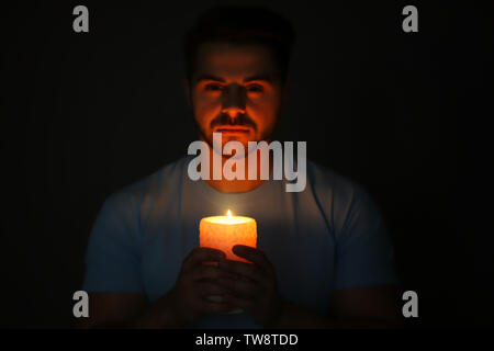Bel giovane con candela che brucia nel buio Foto Stock