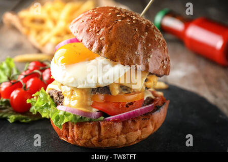 Gustosa burger con uovo fritto sulla piastra di ardesia, primo piano Foto Stock