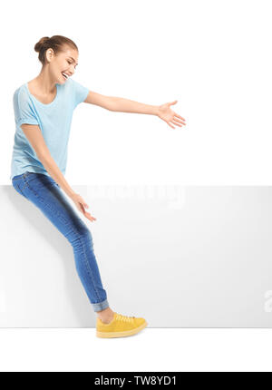 Giovane donna con vuoto pannello pubblicitario su sfondo bianco Foto Stock