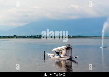 Una barca casa o Shikara giro in barca su Dal lago Srinagar, Jammu e Kashmir in India. Il Grande Himalaya gamma sono visibili a distanza. Immagine presa in Foto Stock