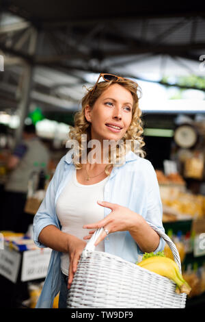 Giovane donna di acquisto su vegetali in stallo al mercato Foto Stock