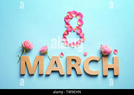 Petali di rosa e lettere di legno su uno sfondo colorato. La giornata internazionale della donna composizione Foto Stock