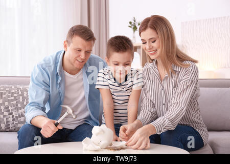 La famiglia felice la rottura salvadanaio con martello a casa Foto Stock