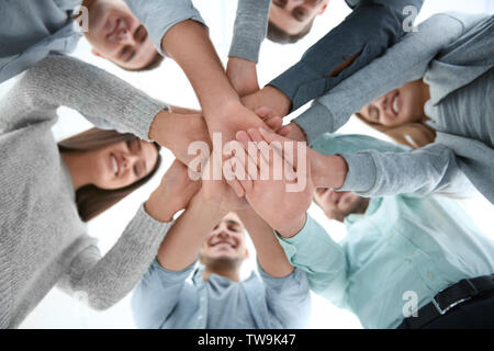 Persone mettere le mani insieme, vista dal basso. La terapia di gruppo Foto Stock