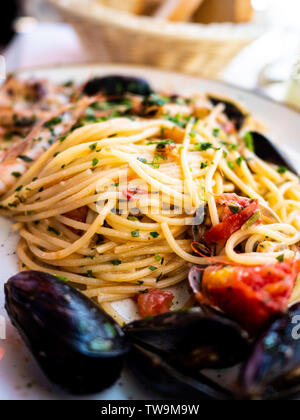 Spaghetti allo scoglio o spaghetti con frutti di mare servita in un piatto bianco con gamberetti e altre conchiglie