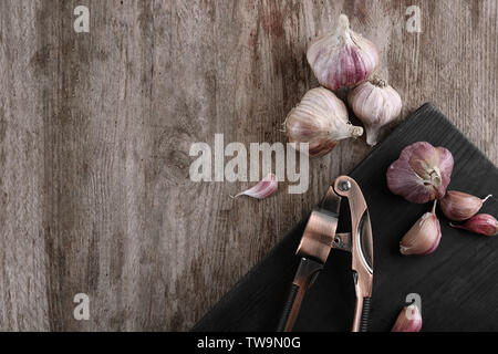 Aglio fresco e frantoio sulla tavola di legno Foto Stock